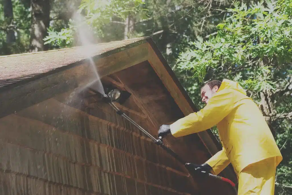 Man pressure washing roof