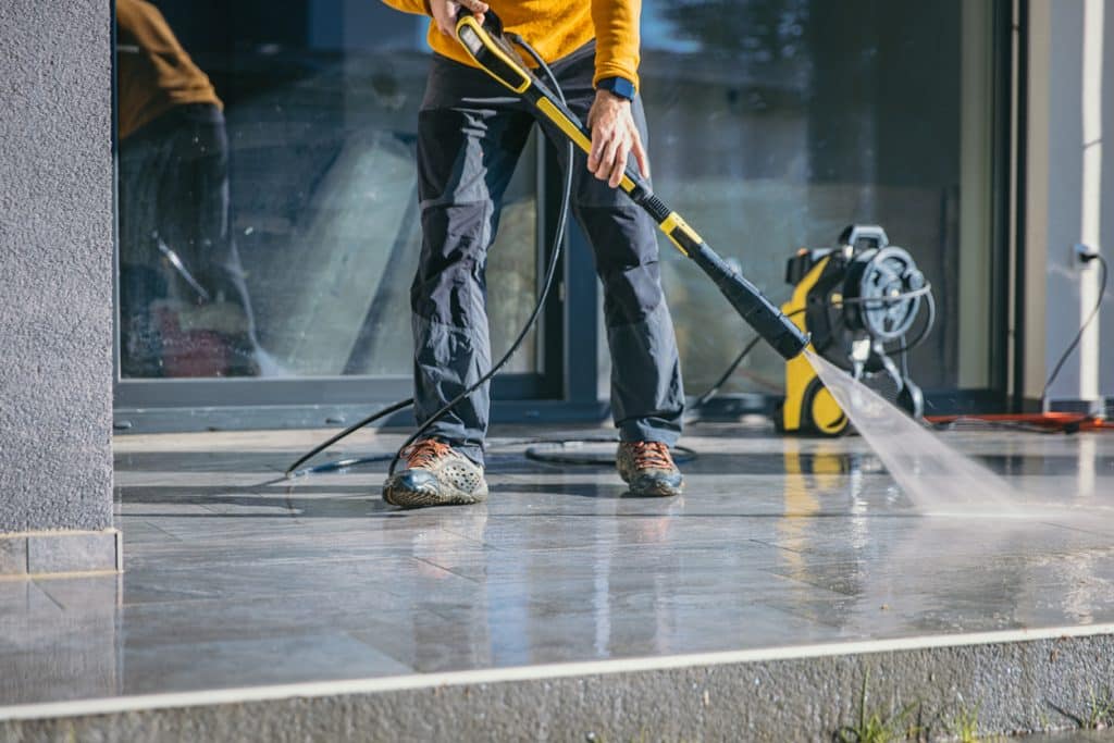 Man cleaning the terrace with high pressure cleaner on beautiful sunny day.